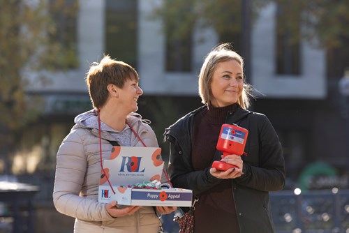 Two female poppy appeal collectors stood outside with a collecting tin and box of poppies